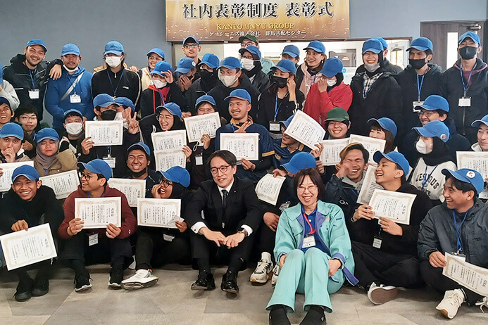 従業員たちが表彰を喜び合い、記念撮影をしている情景